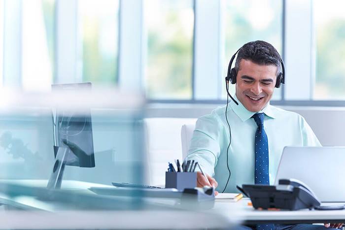 male in headset writing notes