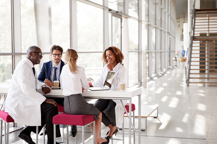 Doctors talking at a table in a modern hospital lobby